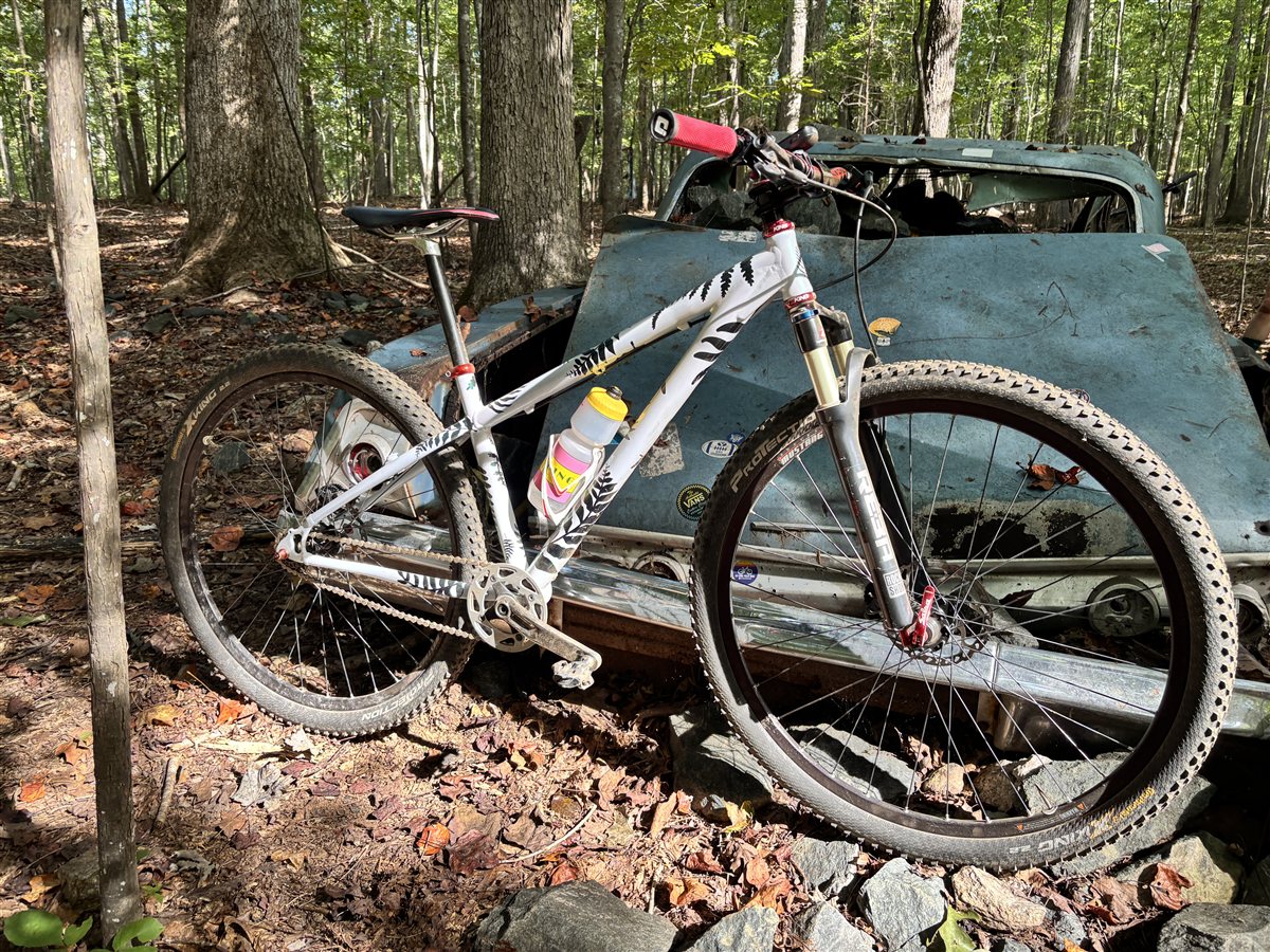 Finished custom painted Big Block Bikes frame leaning against a junkyard car