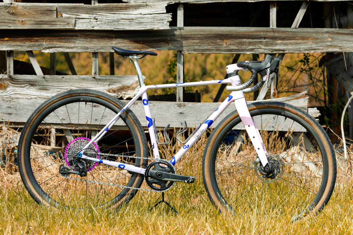 The 401 gravel bike - full profile in a grassy field against an old barn wagon