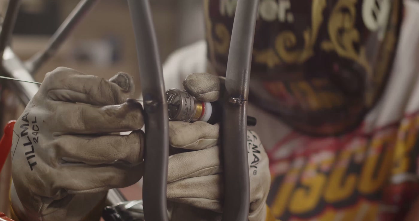 Gloved hands positioning filler rod at a tube junction